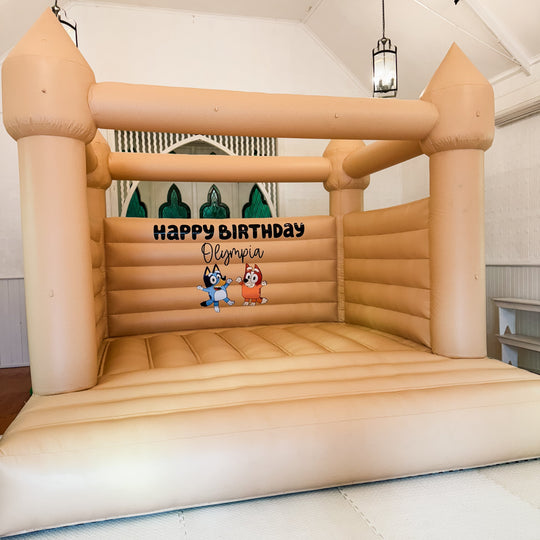 Tan bouncy castle in a chapel hall with a Happy Birthday Olympia decal and Bluey and Bingo characters for party hire in Melbourne