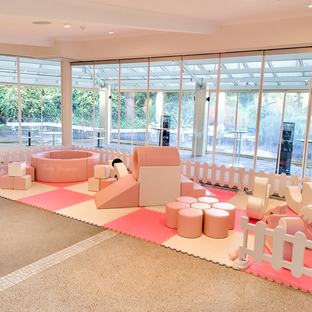Angled view of the baby pink ring tunnel, slide, flower seat and Baby Jasmine ball pit on hot pink and cream mats