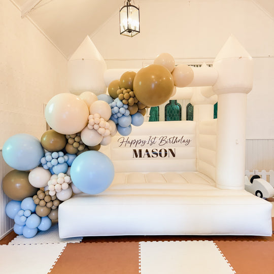 Mason caramel and blue balloon garland on a white bouncy castle with a 1st Birthday Mason decal for party hire in Melbourne