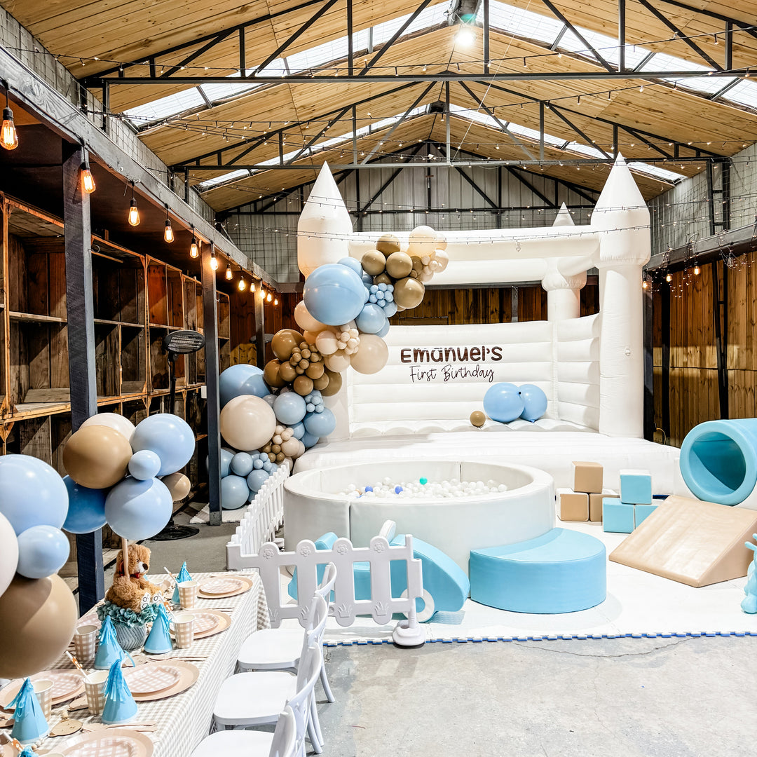 Emanuel balloon garland in pale blue, tan and cream on a white bouncy castle at a warehouse party for party hire in Melbourne