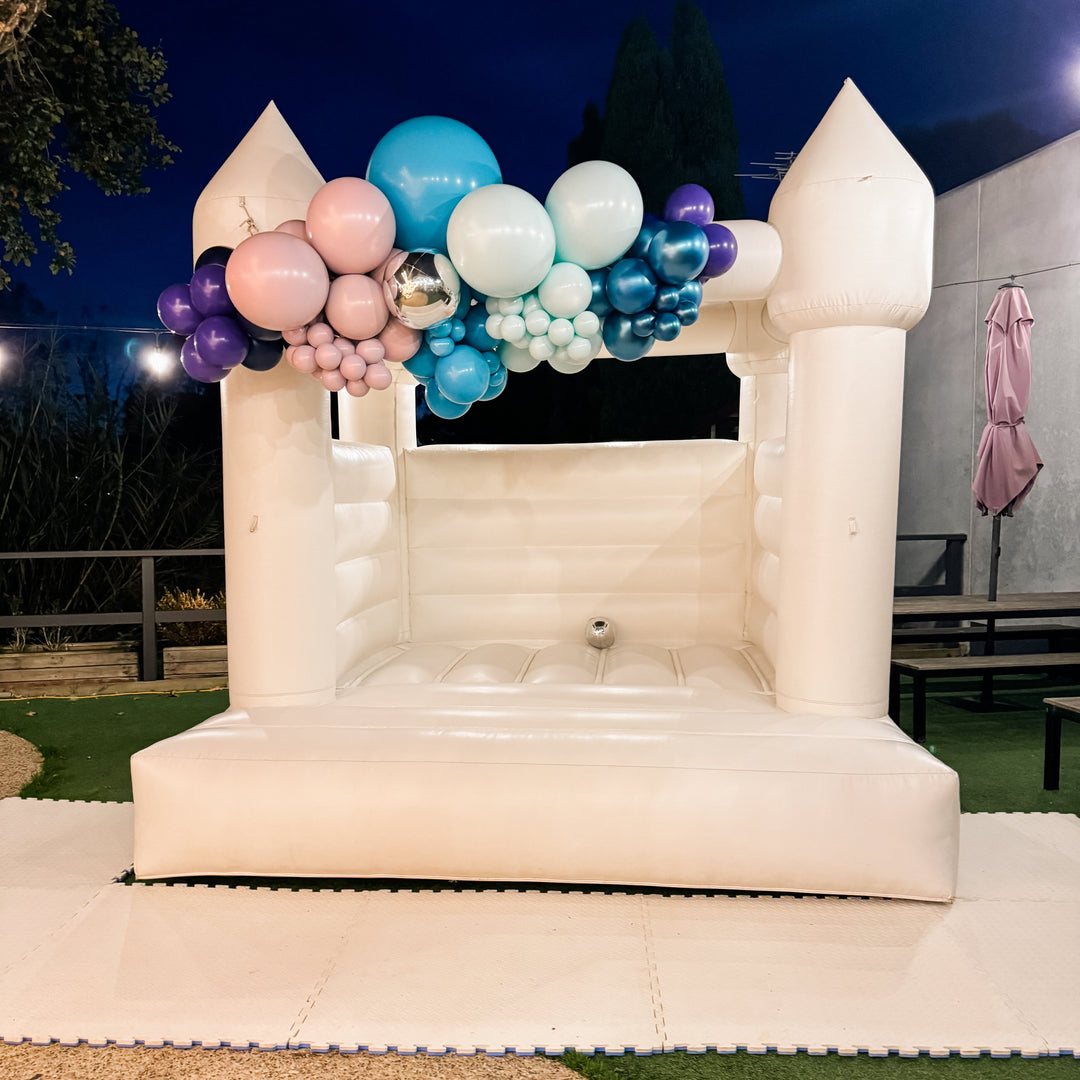 Fi balloon garland in teal, mint, pink, purple and silver on a white bouncy castle at dusk for party hire in Melbourne