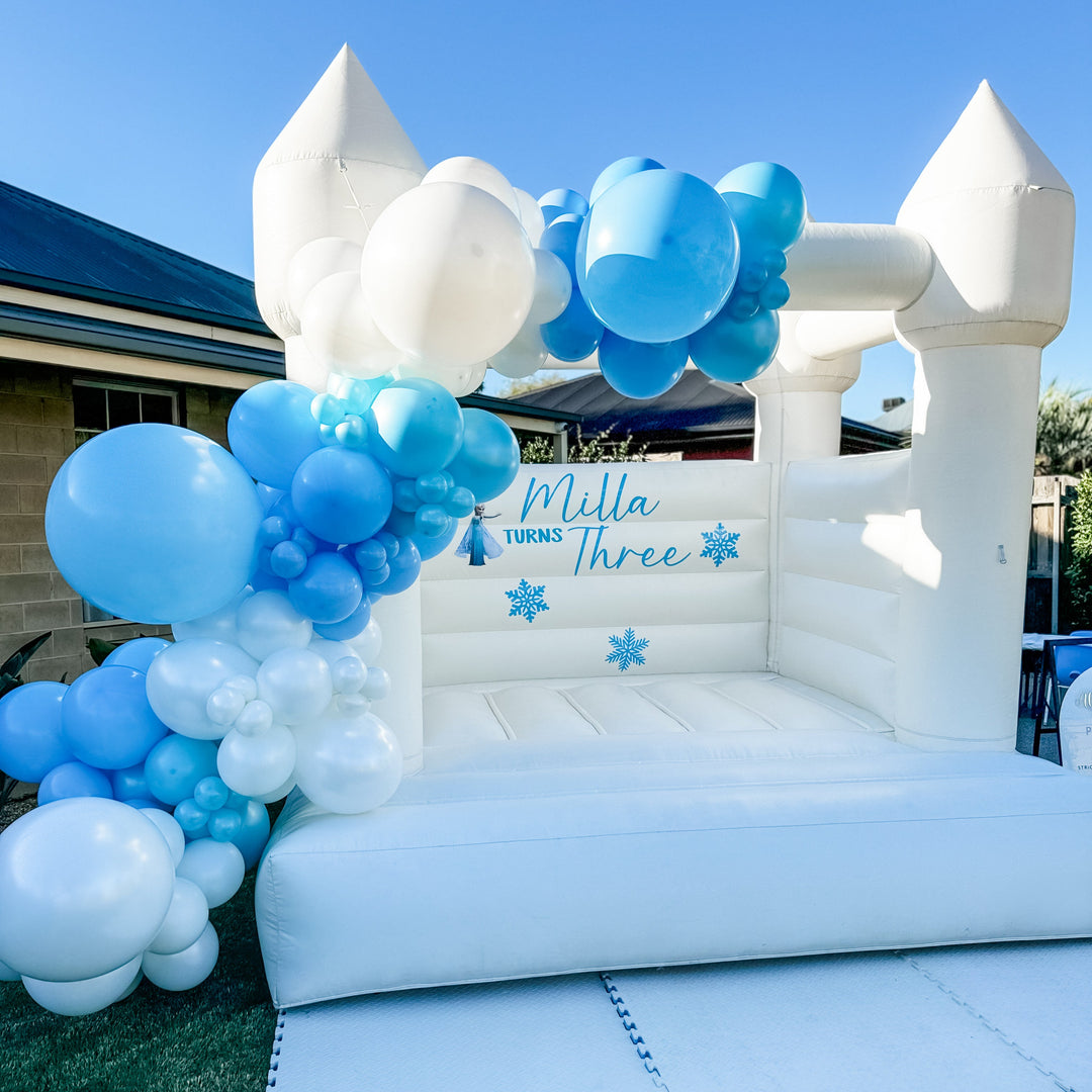 Milla blue and white balloon garland on a white bouncy castle with a Frozen snowflake decal for party hire in Melbourne