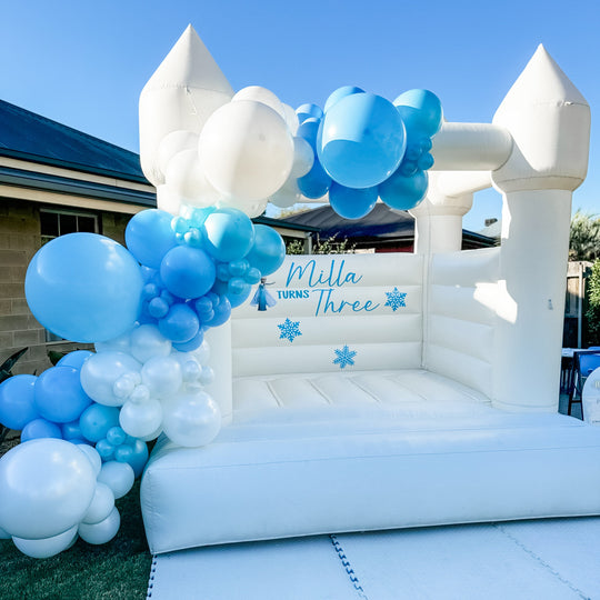 Milla blue and white balloon garland on a white bouncy castle with a Frozen snowflake decal for party hire in Melbourne