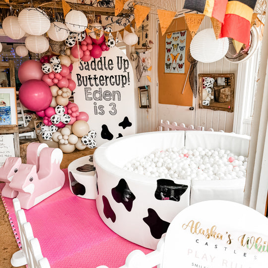 Elsa luxe ball pit with cow print decals and white balls at a farm party with pink balloons for party hire in Melbourne