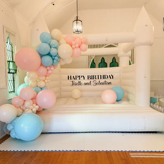 Jiselle pastel pink, blue and cream balloon garland on a white bouncy castle in a chapel hall for party hire in Melbourne