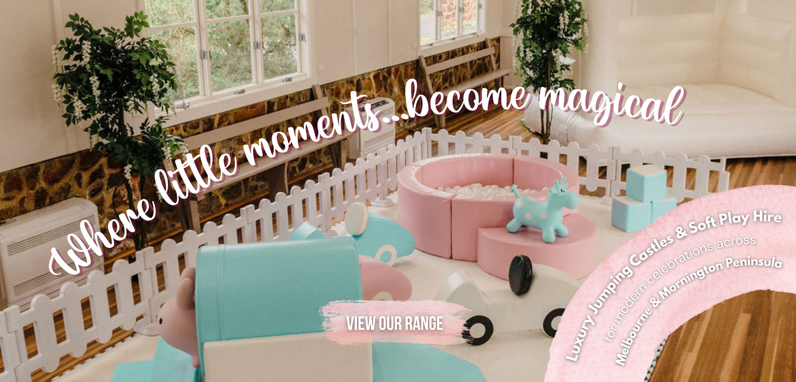 Pink and mint soft play with a pink ball pit and picket fence before a white bouncy castle, for party hire in Melbourne