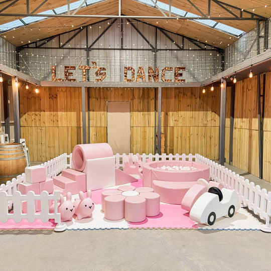 Baby pink soft play, ring tunnel, ball pit and bunny hoppers under a Let's Dance sign for party hire in Melbourne