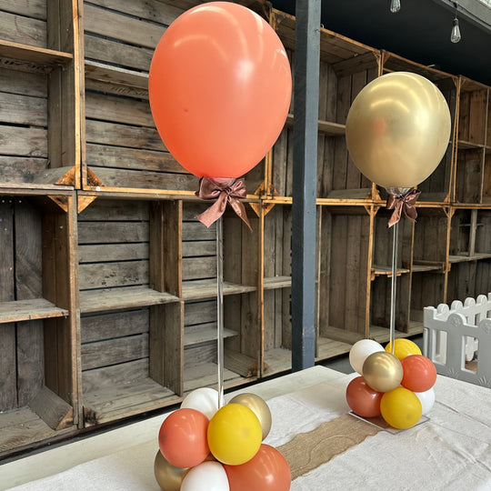 Acrylic tabletop balloon stands with coral and gold balloons, brown ribbon bows and balloon bases for party hire in Melbourne