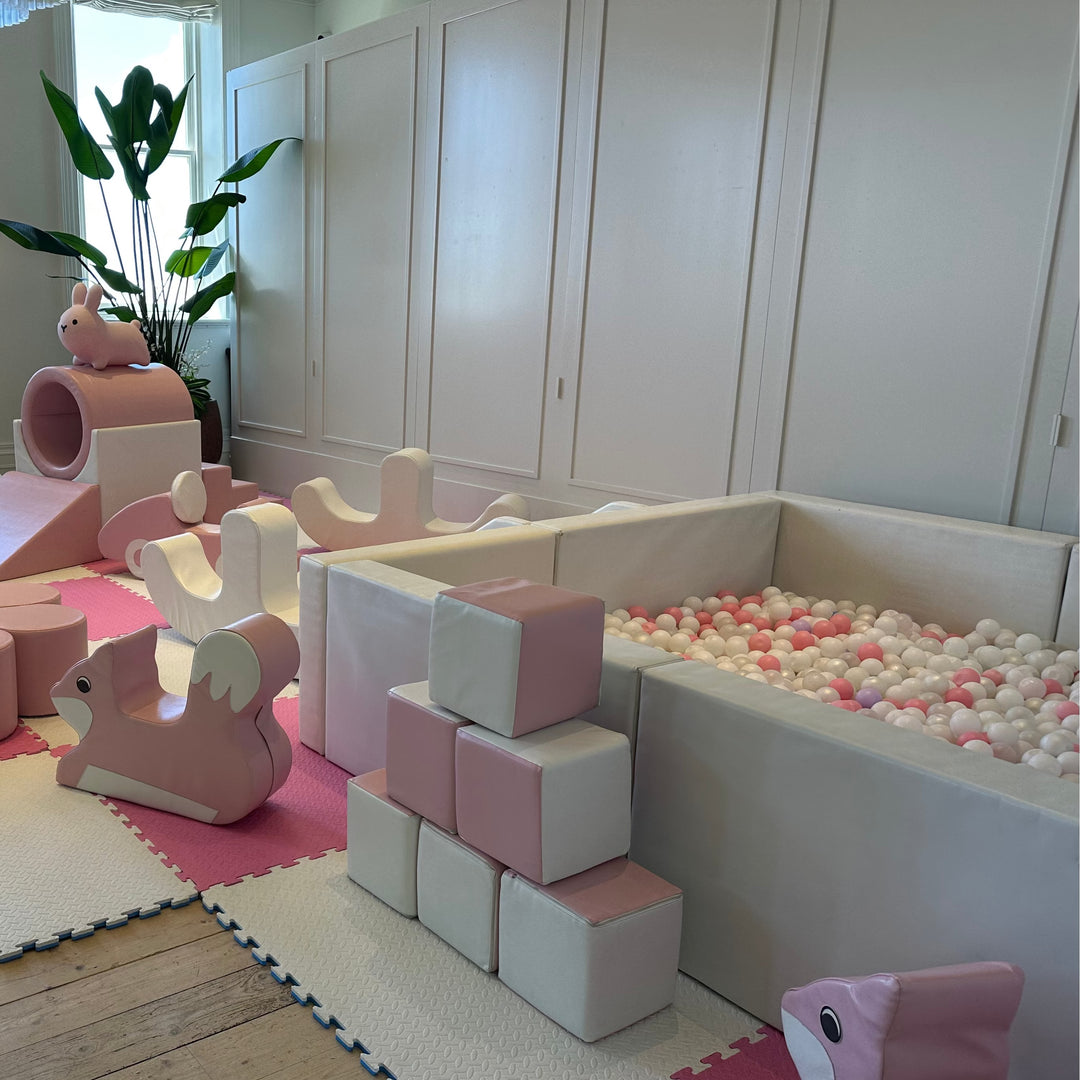 Olaf luxe ball pit in white and pink with pink and white balls in a living room with pink soft play blocks and a bunny rocker