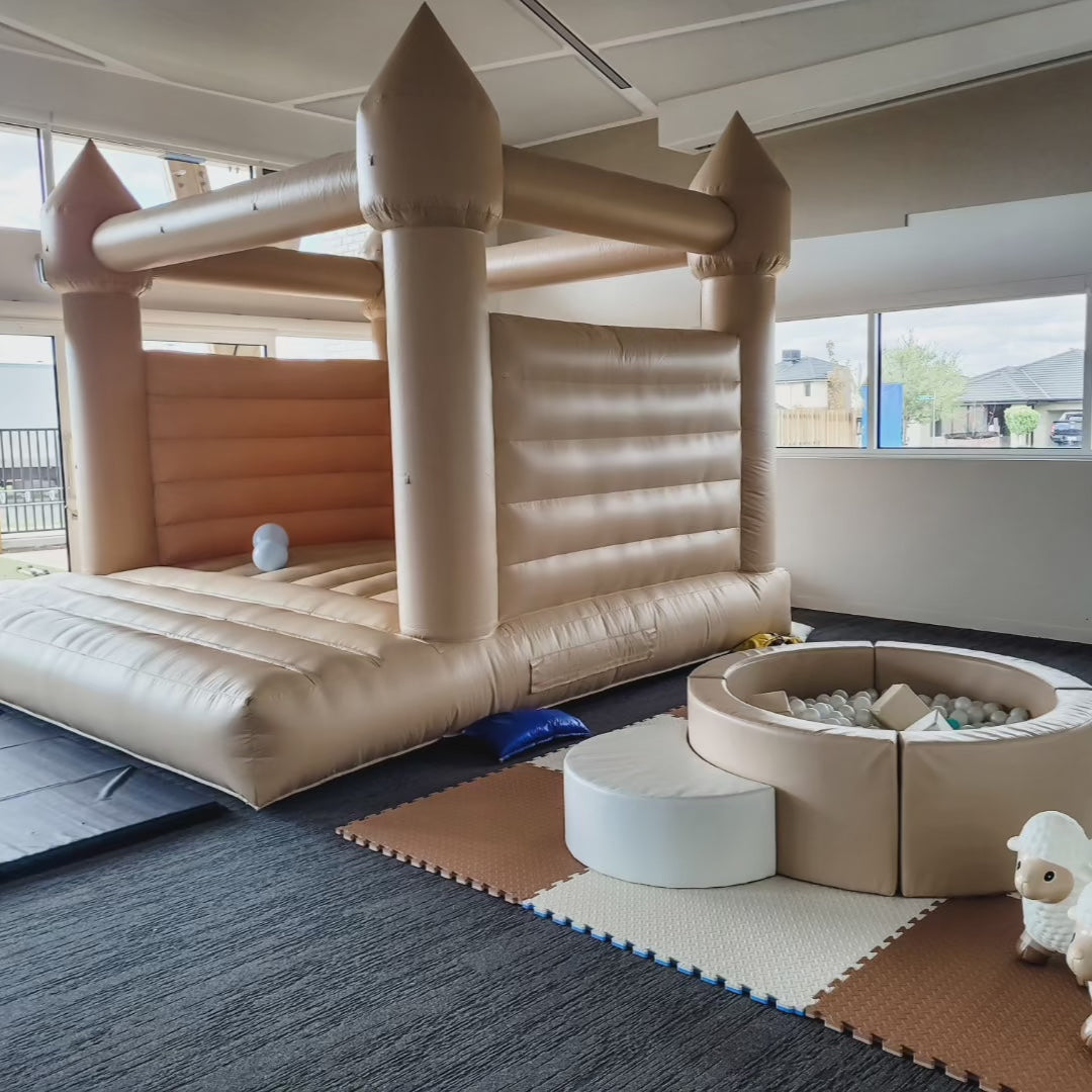 Boho charm set with a summer tan bouncy castle and tan round ball pit on foam mats indoors for party hire in Melbourne