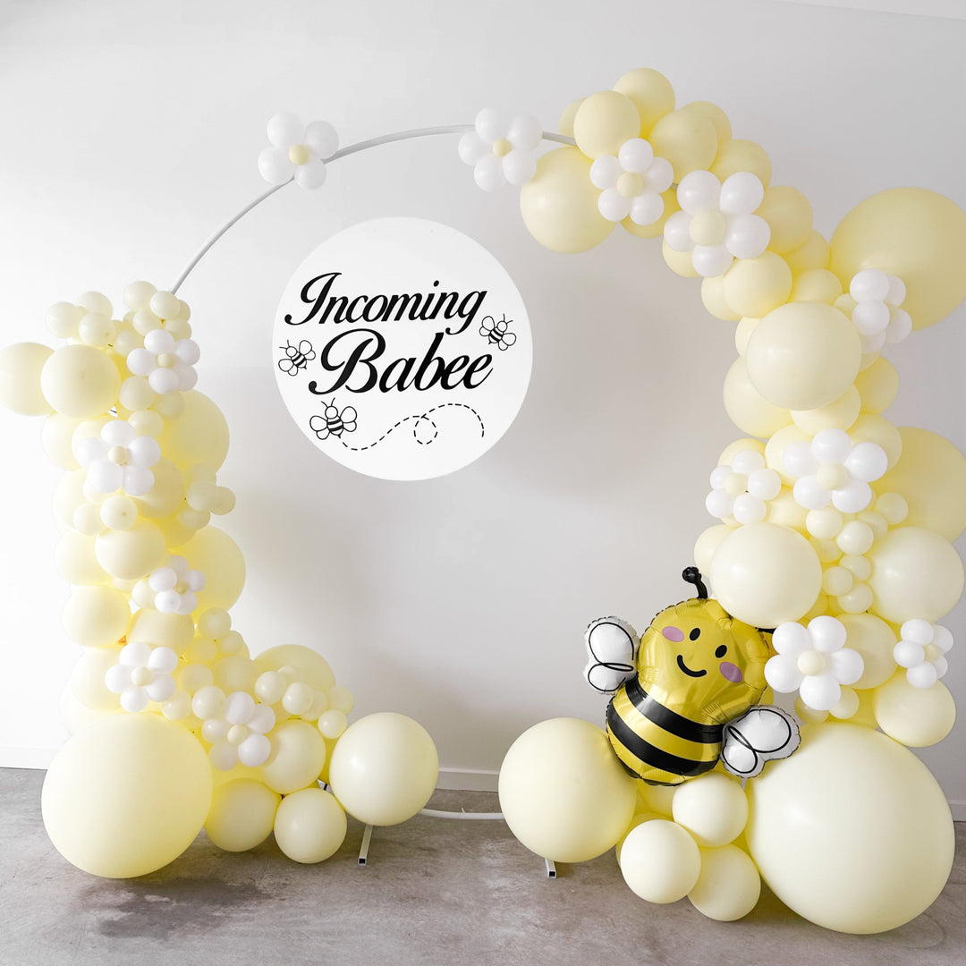 White balloon circular hoop frame with pastel yellow balloons, an Incoming Babee sign and a bee balloon for party hire in Melbourne