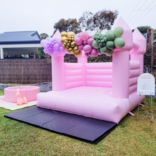 Princess set pastel pink bouncy castle with a lilac and gold balloon garland and pink ball pit for party hire in Melbourne