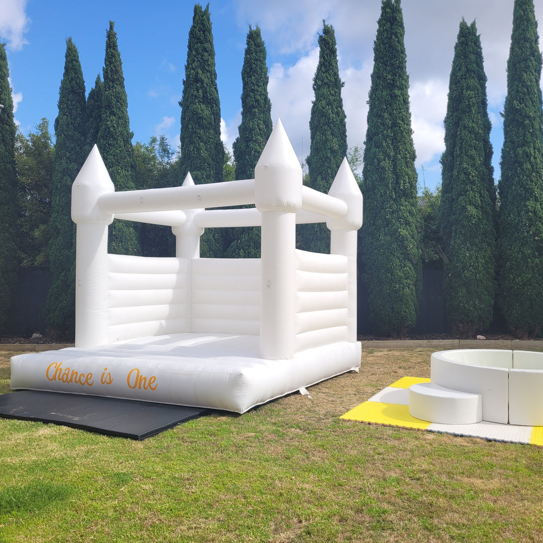 Alaska white castle with an orange Chance is One decal beside a round white ball pit and yellow mats in a hedged backyard