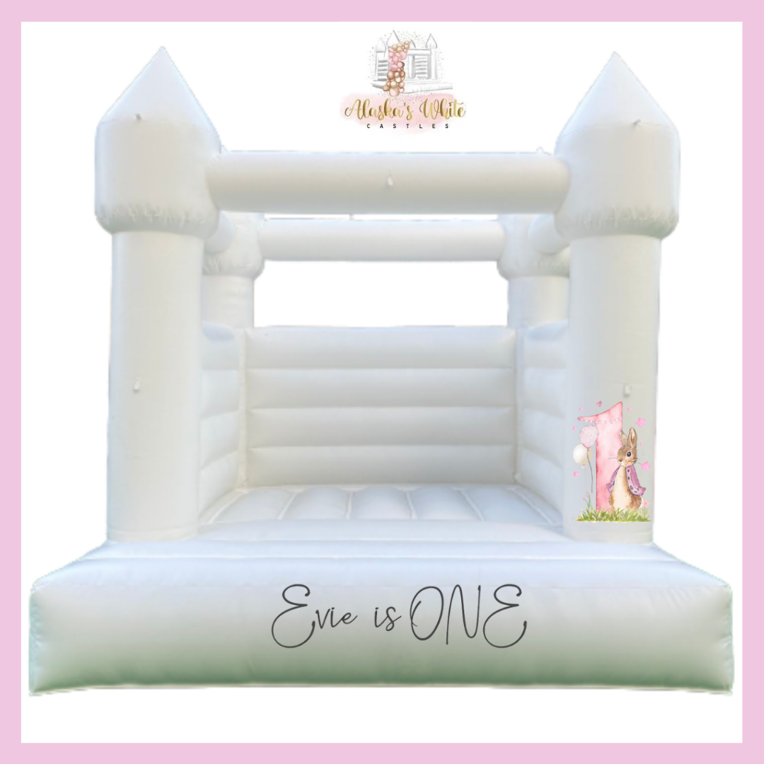Mockup of a white bouncy castle with a Peter Rabbit and pink number one decal on the right pillar and an Evie is ONE decal
