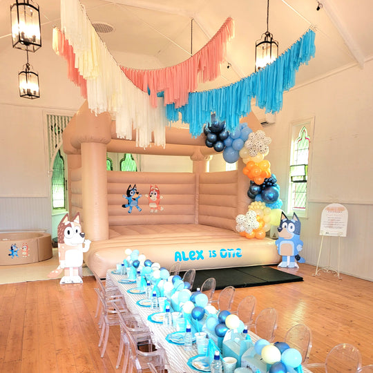 Alex balloon garland in navy, blue, orange and paw print balloons on a tan bouncy castle for party hire in Melbourne